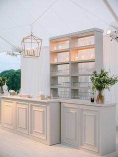 a kitchen with white cabinets and flowers in vases on the counter top next to it