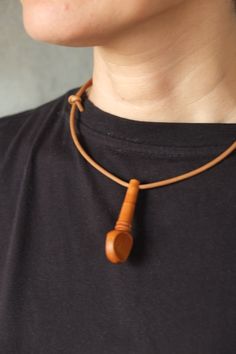 a woman wearing a necklace with a wooden bead on it's end and a leather cord around the neck