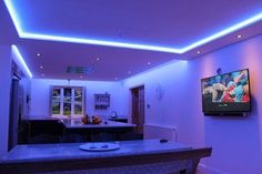 a flat screen tv sitting on top of a wooden table in a living room next to a kitchen