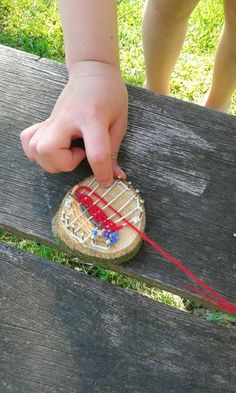 a child's hand is touching a string attached to a piece of wood