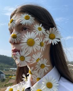 a woman with white and yellow flowers painted on her face in front of the camera