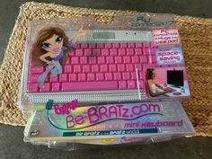 a pink computer keyboard sitting on top of a woven table cloth next to a plastic bag