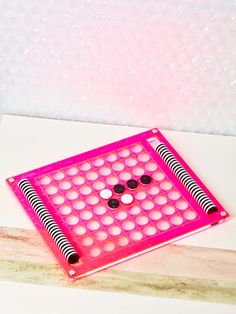 a pink board game sitting on top of a white counter next to a wooden block