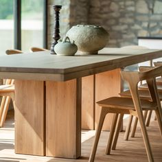 a wooden table with two vases on top of it and chairs around the table