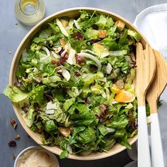 a salad with lettuce, oranges and nuts in a wooden bowl on a table