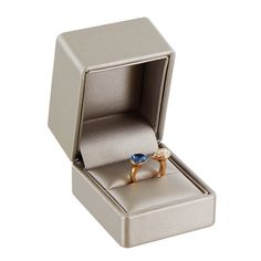 an open ring box with two gold rings inside and one blue stone in the middle