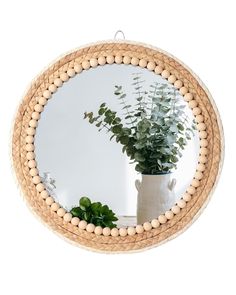 a round mirror sitting on top of a table next to a vase with a plant in it