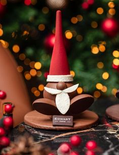 a small gnome figurine sitting on top of a wooden table next to a christmas tree