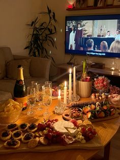 a wooden table topped with lots of food and drinks next to a flat screen tv