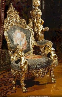 an ornately decorated chair in gold and black with cherubs on the back