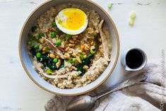 a bowl filled with rice, peas and an egg on top of it next to a spoon