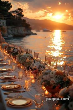 a long table is set up with candles and flowers for an outdoor dinner by the water