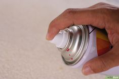 a hand is holding a spray can with something white on the top and red on the bottom