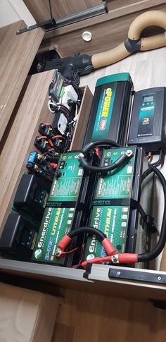 an assortment of batteries and wires in a storage compartment on the floor next to some tools