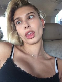 a woman sitting in the back seat of a car making a funny face with her tongue out