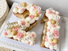 two decorated birthday cakes are on a white tray with gold and pink decorations, one is shaped like the number 50