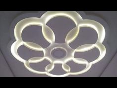 a circular light fixture with white lights on the ceiling and an intricate flower design in the center