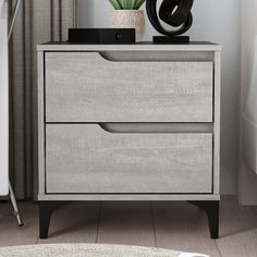 a nightstand with two drawers and a plant on it in a room next to a bed