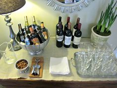 several bottles of wine and glasses on a table next to a bowl full of nuts