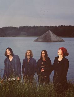 four people standing in front of a body of water