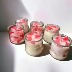 four jars filled with marshmallows on top of a table