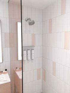 a bathroom with pink and white tiles on the walls, shower head, sink and mirror