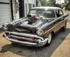 an old black car parked in front of a garage