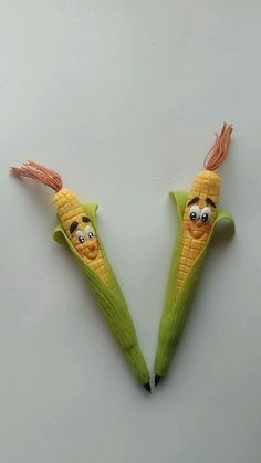 two corn cobs with faces drawn on them