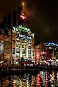 an illuminated sign on top of a building next to the water in front of it