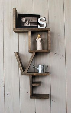 a wooden shelf with two shelves holding figurines on top of it and the word love spelled out