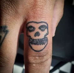 a person with a skull tattoo on their finger