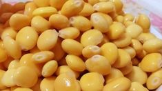 a pile of yellow beans sitting on top of a white plate next to a pink and white checkered table cloth