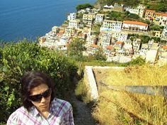 a woman wearing sunglasses standing on the side of a hill