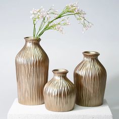 three vases sitting on top of a white block