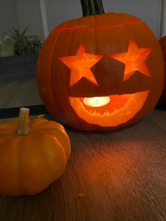 two pumpkins with faces carved to look like stars and one has a light in the middle