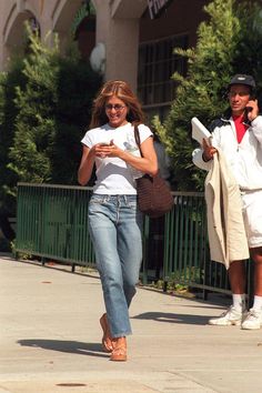 a woman walking down the street while talking on her cell phone and holding a purse