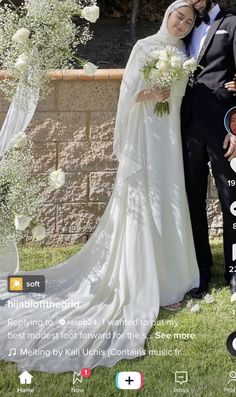 a man and woman standing next to each other in front of a wall with flowers