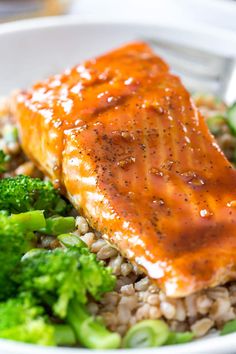 salmon and broccoli in a bowl with brown sauce on top, sitting next to rice