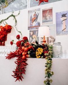 a bunch of red flowers sitting on top of a white wall next to a lamp