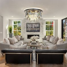 a living room filled with furniture and a chandelier hanging from the ceiling over a fire place