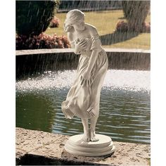 a statue of a woman standing in front of a pond and holding her hands to her chest