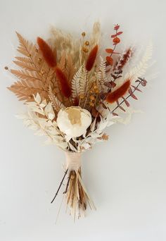 an arrangement of dried flowers and leaves on a white background