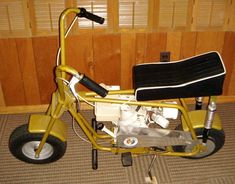 a small yellow motorcycle parked in front of a wooden wall