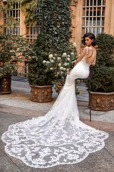 a woman in a wedding dress leaning on a chair with her back to the camera