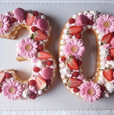 the number 50 is made out of cookies and decorated with strawberries, raspberries, and daisies