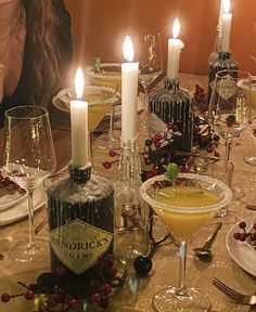 a woman sitting at a table in front of candles and wine glasses with fruit on it