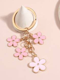 a pink and white flower keychain hanging from a gold plated metal ring