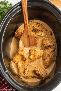 a wooden spoon in a slow cooker filled with meat