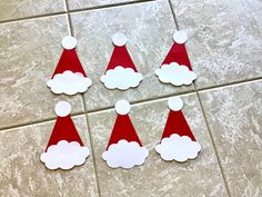 four paper santa hats sitting on top of a tile floor