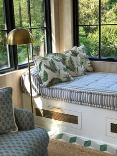 a bed sitting in the middle of a living room next to a window filled with lots of windows